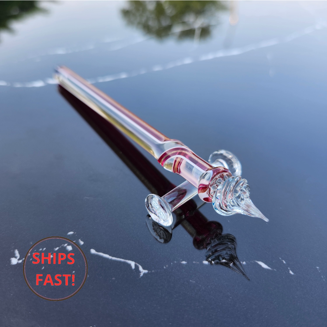 Elegant crimson stripe glass dip pen photographed with ink cleaning orb and accessories