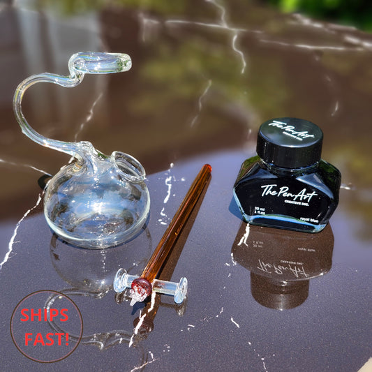 Amber glass dip pen with golden hues and spiral tail resting in wooden gift box