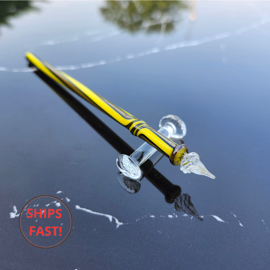 Radiant Volt glass dip pen photographed with ink cleaning orb, pen rest, and creative desk setup